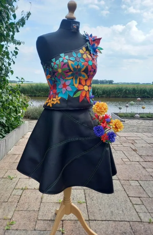 Korset van bloem-applicaties in kleurrijk kunstleer op zwarte rok, in atelier-tuin Emmeloord