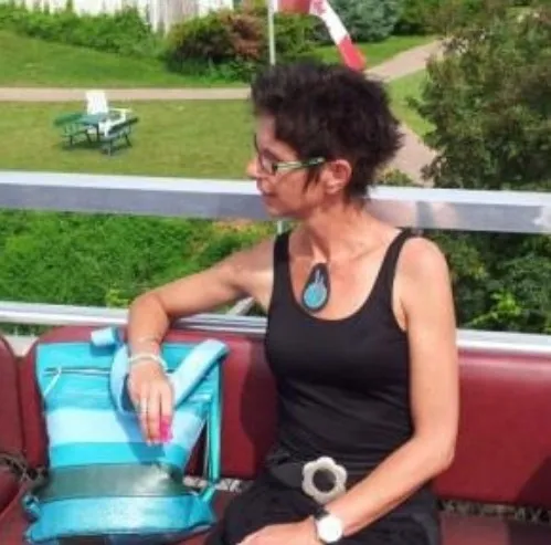 Trudi de Kreek in haar atelier-tuin met een turquoise zelfgemaakte schoudertas