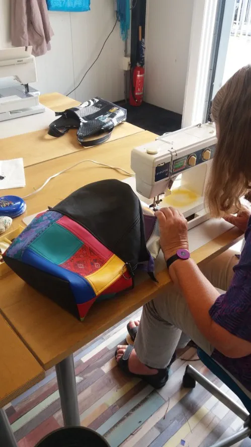 Werktafel met losse stukken kunstleer en gereedschap voor het maken van een tas